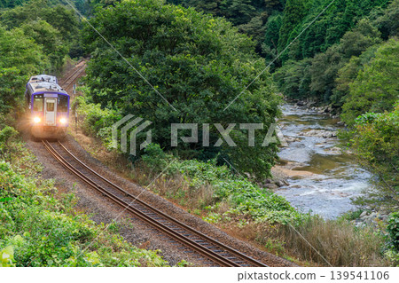 清晨,一列柴油火車在關西本線上穿過一片深綠色的山谷,駛向加茂 清晨,一列柴油火車在關西本線上穿過一片深綠色的山谷,駛向加茂 139541106