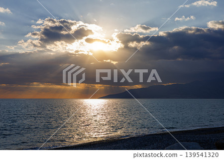 Sunlight rays breaking through clouds over a sea horizon Sunlight rays breaking through clouds over a sea horizon 139541320