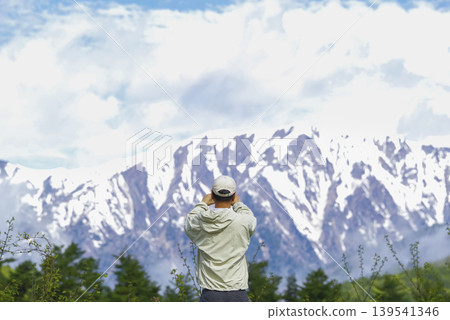 A male traveler photographs the spectacular scenery of the Northern Alps. 139541346