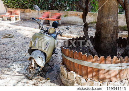 Old vintage scooter parked on a stone paved courtyard Old vintage scooter parked on a stone paved courtyard 139541543