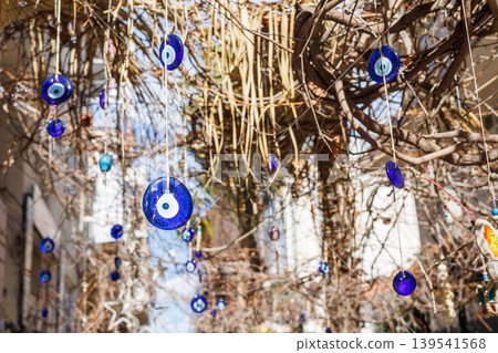 Blue evil eye beads hanging from tree branches Blue evil eye beads hanging from tree branches 139541568