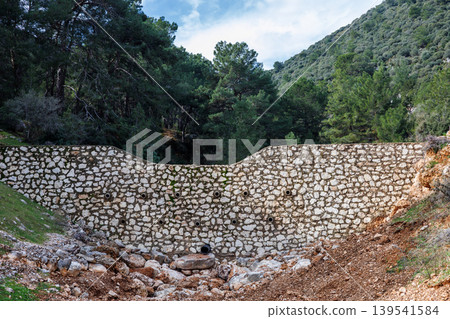 Stone masonry dam wall in a forest ravine Stone masonry dam wall in a forest ravine 139541584