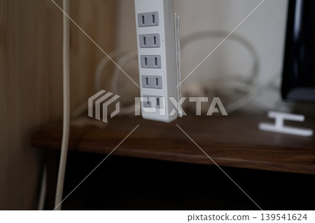延長線。一個白色的五孔電源插座從上方懸掛著。室內。 139541624