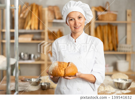 Female baker worker show loafs of breads Female baker worker show loafs of breads 139541632