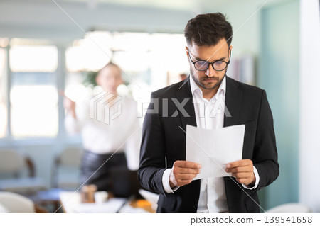 Sad man standing in office, he holding resignation papers 139541658