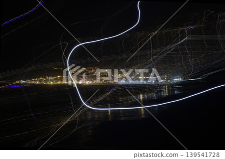 Abstract long exposure light trails over illuminated coastal city at night Abstract long exposure light trails over illuminated coastal city at night 139541728