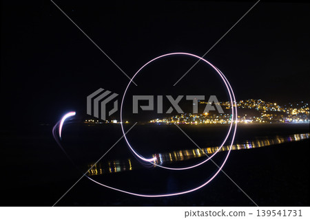 Creative long exposure light painting spiral over coastal city night landscape Creative long exposure light painting spiral over coastal city night landscape 139541731