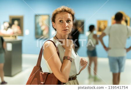 Woman looks at hall of paintings and sculptures Woman looks at hall of paintings and sculptures 139541754