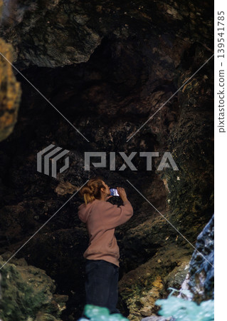 Young woman taking with smartphone inside a dark rock cave Young woman taking with smartphone inside a dark rock cave 139541785
