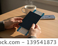 Hands holding passport and boarding passes, with coffee and phone on a table 139541873