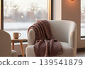 Cozy armchair with a warm blanket and steaming mug by a window 139541879