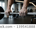 Mans chalked hands gripping a barbell in a gym 139541888