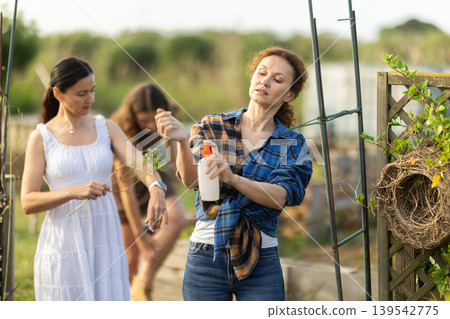 Women spray mosquito repellent on their legs and arms while working in farm and garden Women spray mosquito repellent on their legs and arms while working in farm and garden 139542775