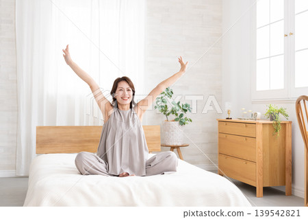 Middle-aged woman stretching in bed Middle-aged woman stretching in bed 139542821