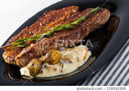 Beef steak with mushrooms sauce branch of rosemary at black plate 139542906