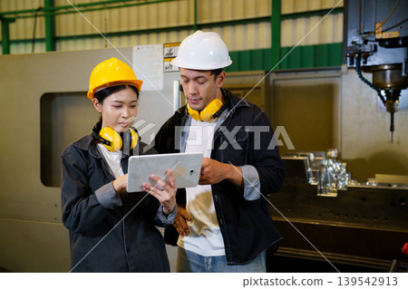 Industrial engineers operating machine control panel in factory environment 139542913