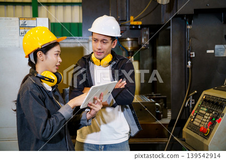 Industrial engineers operating machine control panel in factory environment 139542914