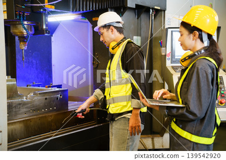 Industrial engineers operating machine control panel in factory environment 139542920