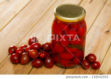 Glass jar with pickled tomatoes and fresh tomatoes 139542935