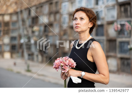 Woman brought flowers to the cemetery and cries over the death of beloved relative Woman brought flowers to the cemetery and cries over the death of beloved relative 139542977