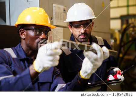 Engineers using tablet checking machinery in manufacturing factory 139542982