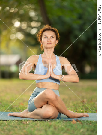 Lotus pose - slim woman doing yoga outdoors in park 139543023