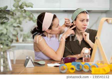 Two women looking at themselves in mirror Two women looking at themselves in mirror 139543112