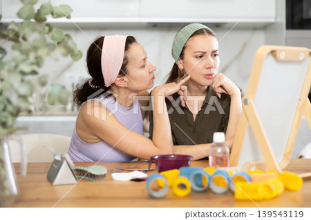 Two women looking at themselves in mirror Two women looking at themselves in mirror 139543119