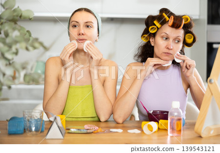 Two women cleanse their face with cotton pads Two women cleanse their face with cotton pads 139543121