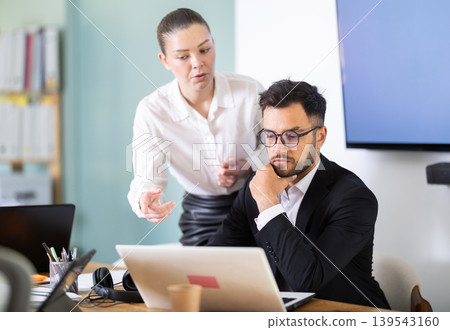 Man works at laptop and demonstrates project to girl colleague 139543160