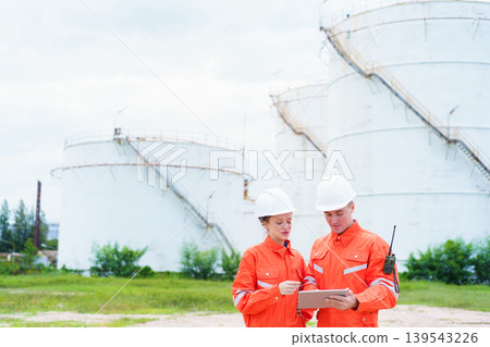 Two engineers surveying oil storage tank in energy plant Two engineers surveying oil storage tank in energy plant 139543226