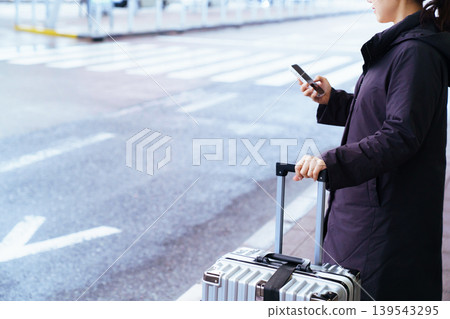 Asian woman with suitcase using smartphone at airport Asian woman with suitcase using smartphone at airport 139543295