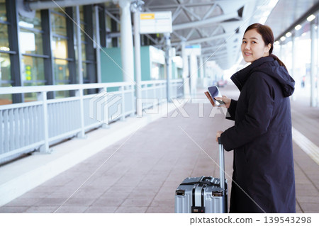 Asian woman with suitcase using smartphone at airport Asian woman with suitcase using smartphone at airport 139543298