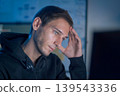 Software developer feeling stressed while working on programming code late at night 139543336