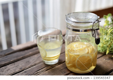 A bottle of homemade lemon syrup and hot lemonade placed on the windowsill. 139543347