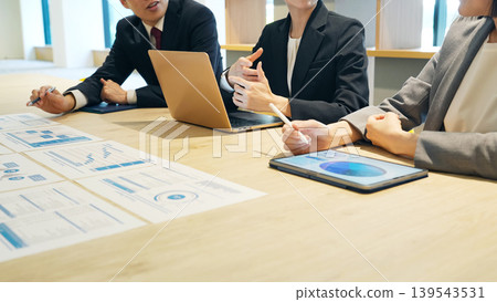 A group of business people having a meeting while looking at documents in the office. A group of business people having a meeting while looking at documents in the office. 139543531