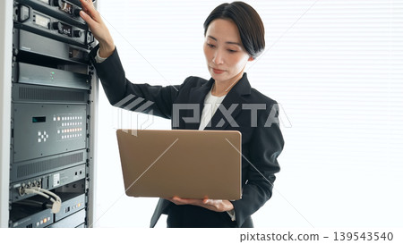 Female engineer inspecting a server Female engineer inspecting a server 139543540