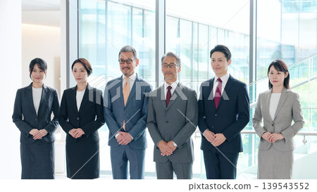一群年齡各異的商務人士,男女都有,在大廳裡排成一列。 一群年齡各異的商務人士,男女都有,在大廳裡排成一列。 139543552