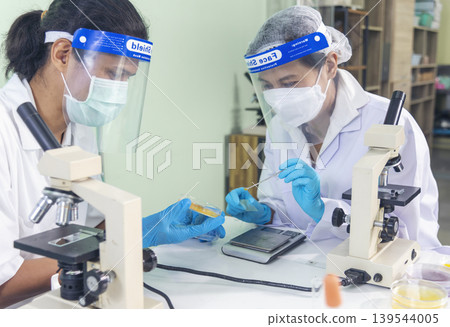 Scientist man woman working together team partner look into Microscope research in science laboratory. Two Asian scientist use microbiology microscope chemistry lab equipment. Biochemistry researcher Scientist man woman working together team partner look into Microscope research in science laboratory. Two Asian scientist use microbiology microscope chemistry lab equipment. Biochemistry researcher 139544005