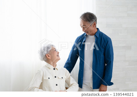 A woman sitting on a chair and a man standing next to her. Lifestyle image 139544021