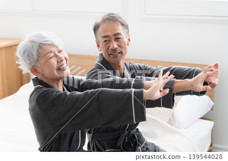 Senior couple sitting on the bed in a gown coat Lifestyle image Senior couple sitting on the bed in a gown coat Lifestyle image 139544028