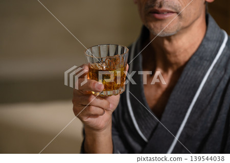 Senior man wearing a gown and holding a rocks glass Lifestyle image Senior man wearing a gown and holding a rocks glass Lifestyle image 139544038