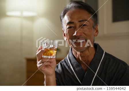 Senior man wearing a gown and holding a rocks glass Lifestyle image Senior man wearing a gown and holding a rocks glass Lifestyle image 139544042
