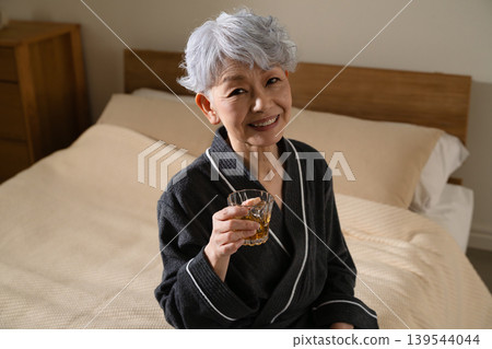 Senior woman wearing a gown and holding a rocks glass Lifestyle image Senior woman wearing a gown and holding a rocks glass Lifestyle image 139544044