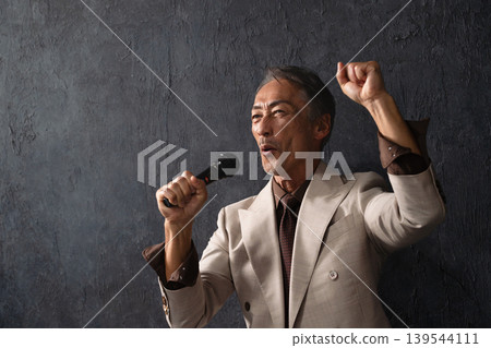Senior man singing passionately with a microphone Lifestyle image Senior man singing passionately with a microphone Lifestyle image 139544111