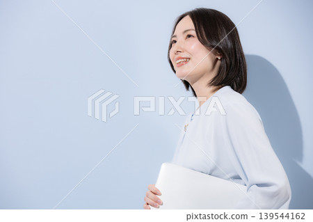 A positive portrait of a smiling woman with her arms crossed against a light blue background, conveying the confidence and self-assurance of a cool woman, and her future and goals. A positive portrait of a smiling woman with her arms crossed against a light blue background, conveying the confidence and self-assurance of a cool woman, and her future and goals. 139544162