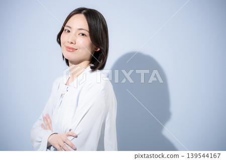 一張正面的肖像照,照片中一位面帶微笑的女性雙臂交叉,背景是淺藍色,展現出一位冷靜自信的女性直視鏡頭的形象。 一張正面的肖像照,照片中一位面帶微笑的女性雙臂交叉,背景是淺藍色,展現出一位冷靜自信的女性直視鏡頭的形象。 139544167