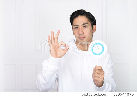 一位面帶微笑的男士拿著正確答案的記號。 一位面帶微笑的男士拿著正確答案的記號。 139544879