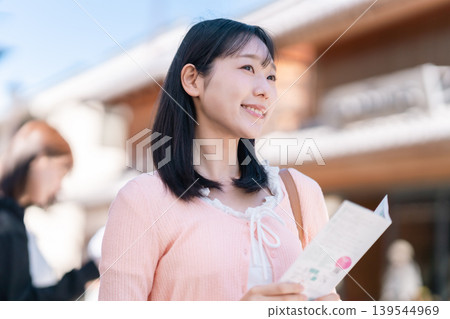 一位女士在川越——「小江戶」——的街道上漫步,手持宣傳冊,背景是川越的鐘樓。 (埼玉縣旅遊圖片) 一位女士在川越——「小江戶」——的街道上漫步,手持宣傳冊,背景是川越的鐘樓。 (埼玉縣旅遊圖片) 139544969
