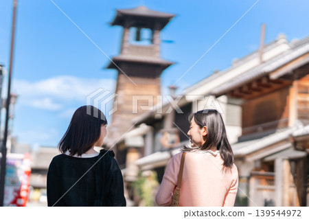 兩名年輕女子漫步街頭,背景是川越時之鐘。這是她們的埼玉縣之旅,在鎮上閒晃觀光。 兩名年輕女子漫步街頭,背景是川越時之鐘。這是她們的埼玉縣之旅,在鎮上閒晃觀光。 139544972
